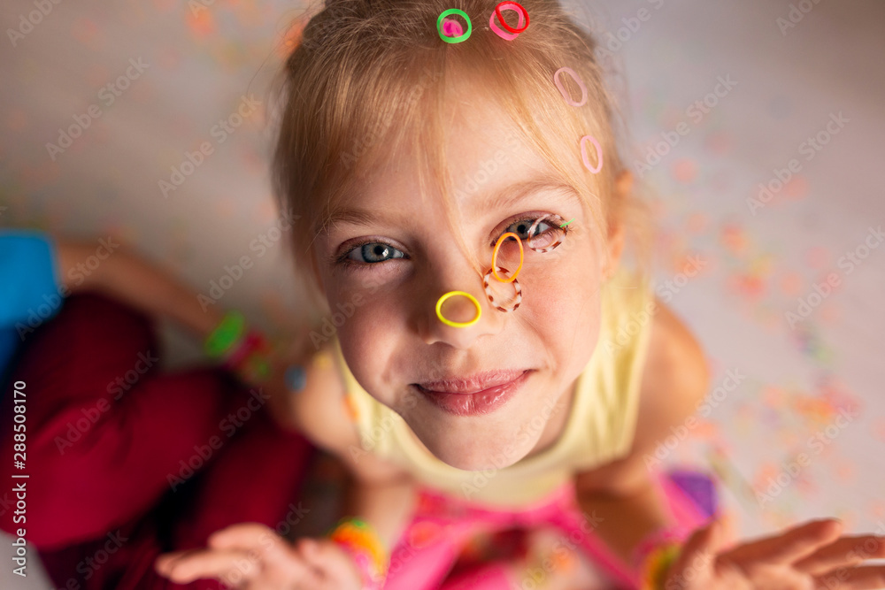 happy kids, a boy and a girl, 7-8 years old are engaged in hobbies, weave colored bracelets from rubber bands together, a mess, poured elastic bands on the face