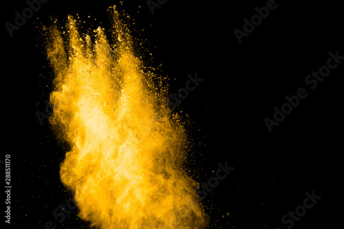 Yellow dust particles explosion on black background.Yellow powder dust splash.