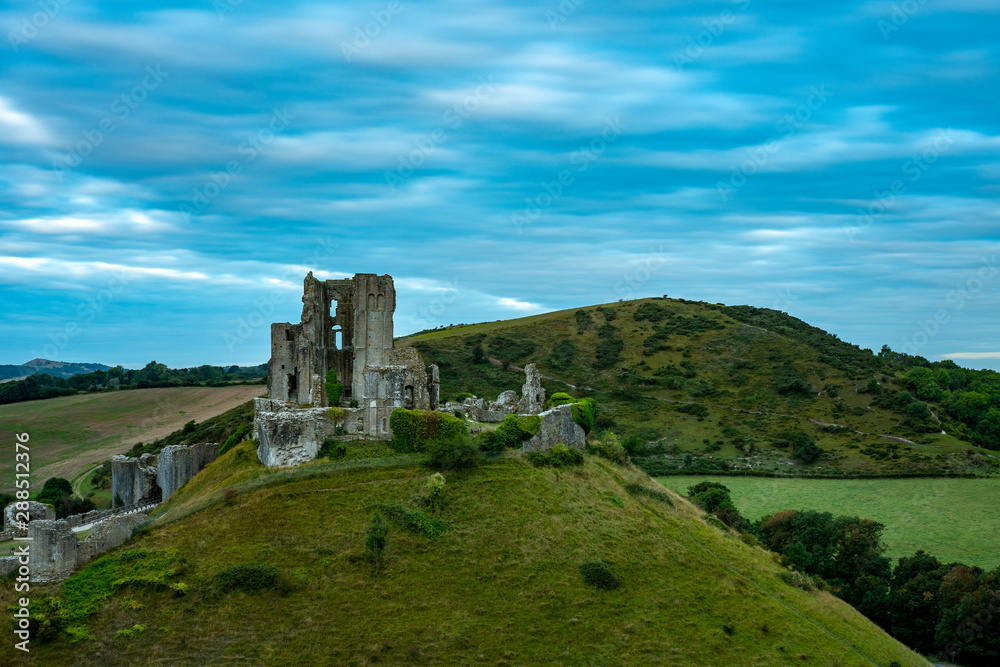 Ruins of Corfe Castle during blue hour with Purbeck hills behind in a long exposure photography, Isle of Purbeck, Dorset, England