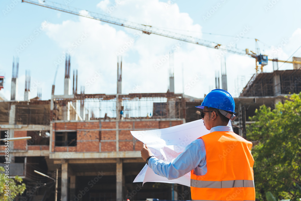 Civli engineer with blue safety helmet and sunglasses holding blueprint or drawing at construction site. Civli engineer with blue safety helmet and sunglasses holding blueprint or drawing at construction site.