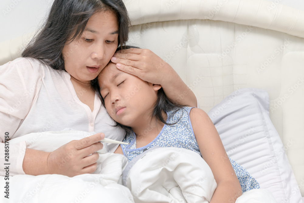 Mother checking temperature of her sick daughter Mother checking temperature of her sick daughter