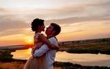 Loving couple, a guy and a girl kiss and hug at sunset on the mountain against the background of the river. Wedding day