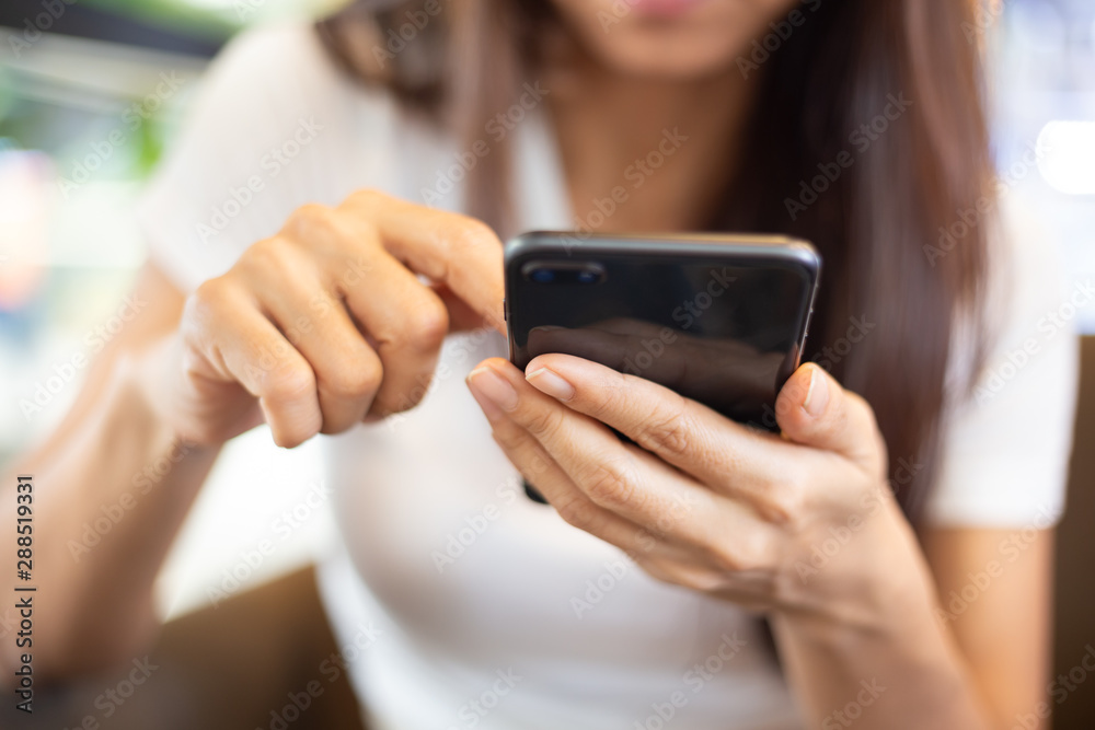 Asian Women sitting in a coffee shop using a smart phone for talking, reading and sending messages. Asian Women sitting in a coffee shop using a smart phone for talking, reading and sending messages.