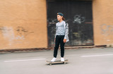 Teenager skateboarder boy riding on skateboard on asphalt road near a grunge graffiti wall. Youth generation Freetime spending concept image.
