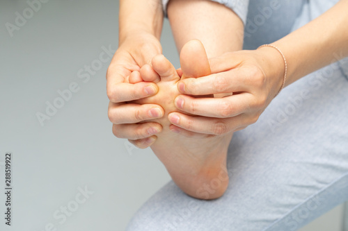 Принти на полотні A closeup view of a caucasian woman inspecting and rubbing feet, separating the toes of bare foot, detailed view with copy-space on the left