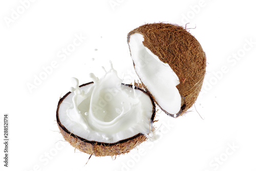 Coconut broken in half. A splash of coconut milk.