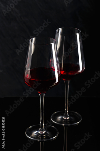 Bottle and glass of red wine on black background