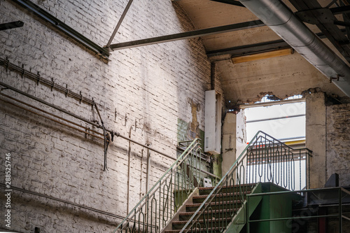 Interior view of the hole of demolishing wall at the top of steel staircase inside old brick building of former abandon factory or industrial building.