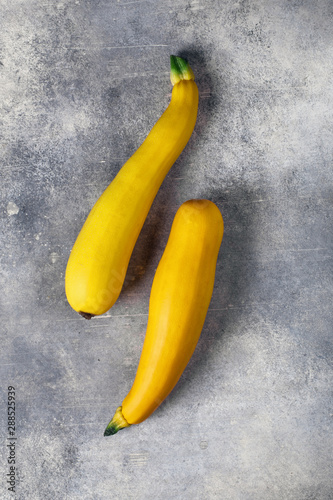 Two yellow zucchini on concrete background, top view