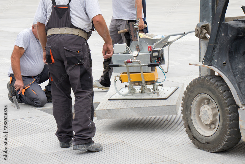 Obraz premium Lifting the stone slab with vacuum magnet device, block paving equipment machinery