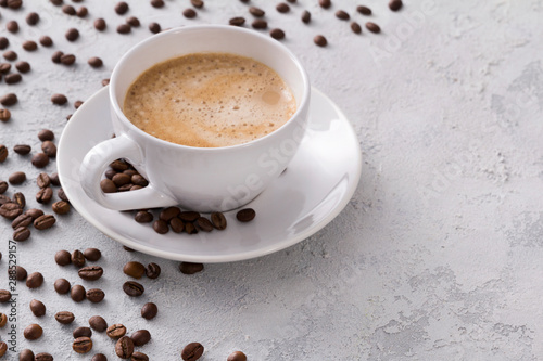 A cup of delicious hot cappuccino and beans on a gray concrete table