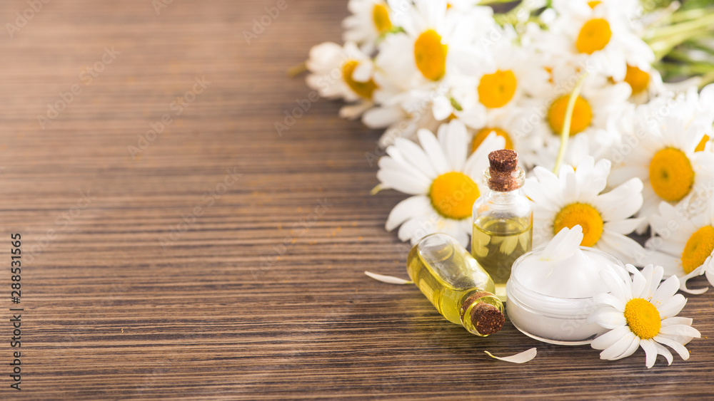 Closeup of bottle with essential oil and cream of chamomile Closeup of bottle with essential oil and cream of chamomile
