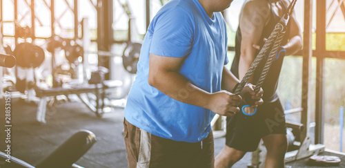 Fat fitness men with trainer exercising at fitness gym. Man diet lifestyle concept to reduce belly and shape up healthy stomach muscle. Fat man, Fat boy.