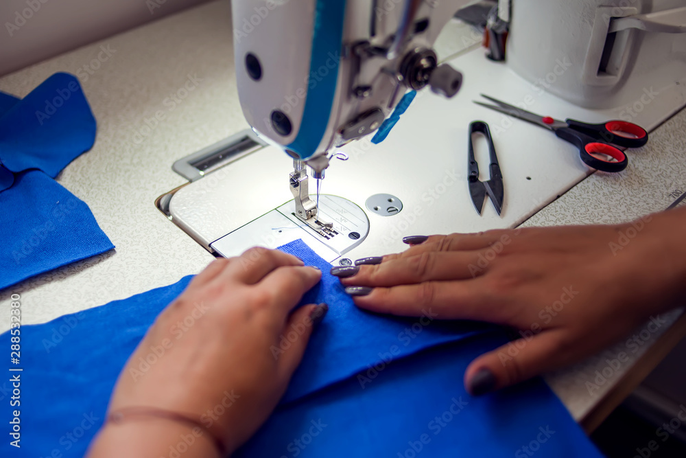 Woman works with sewing machine. Manufacture of wearing concept