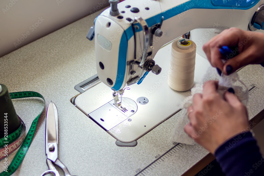 Woman works with sewing machine. Manufacture of wearing concept