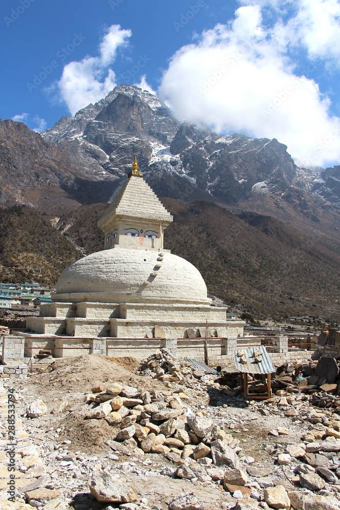 Old typical white Buddhist stupa (chorten) near Khunde village at the foot of Khumbila mountain in Sagarmatha national park. Above is a standard drawing of the eyes of Buddha. Religion concept.