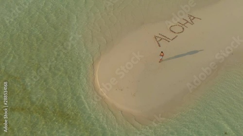 aerial tropical sandbar Aloha written made from starfishes on candaraman sandbar. drone turning around for travel couple walking on sandbar at sunset in Balabac, Palawan, Philippines photo