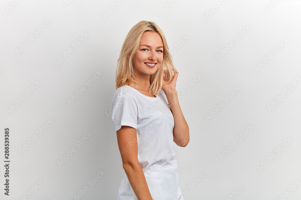Young caucasian blonde girl enjouing her new hairstyle, close up portrait, beauty concept, isolated white background Young caucasian blonde girl enjouing her new hairstyle, close up portrait, beauty concept, isolated white background