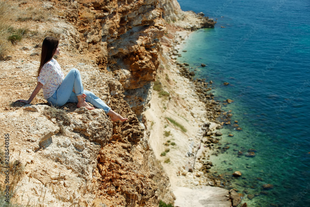 Woman and beautiful landscape. A woman sits on a mountain overlooking the sea. Woman and beautiful landscape. A woman sits on a mountain overlooking the sea.
