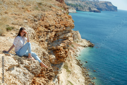 Woman and beautiful landscape. A woman sits on a mountain overlooking the sea. 