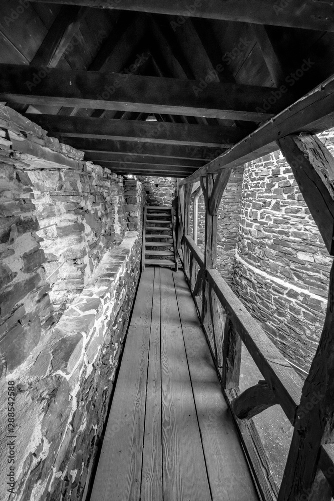 Schwarz Weiß Aufnahme - Holzweg und Holztreppe führen in einer Burgruine zum Turm