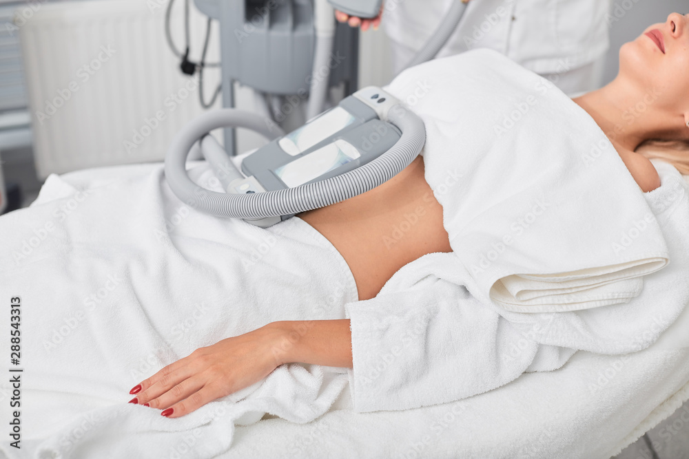relaxed calm woman taking treatment in the clinic. close up cropped side view photo. machine for weight loss relaxed calm woman taking treatment in the clinic. close up cropped side view photo. machine for weight loss