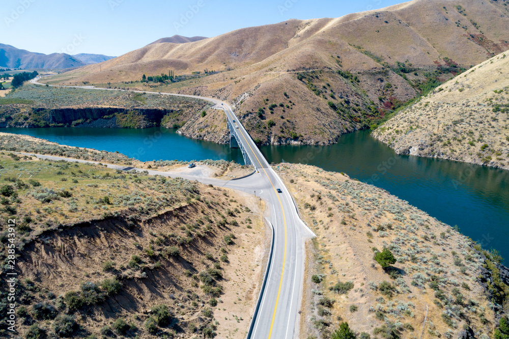 Cars drive across a bridge the leads over a reservoir through a desert