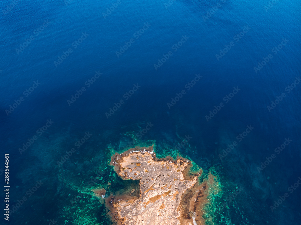 Top view Azure blue sea with waves beating on beach and rocks. Aerial photo.