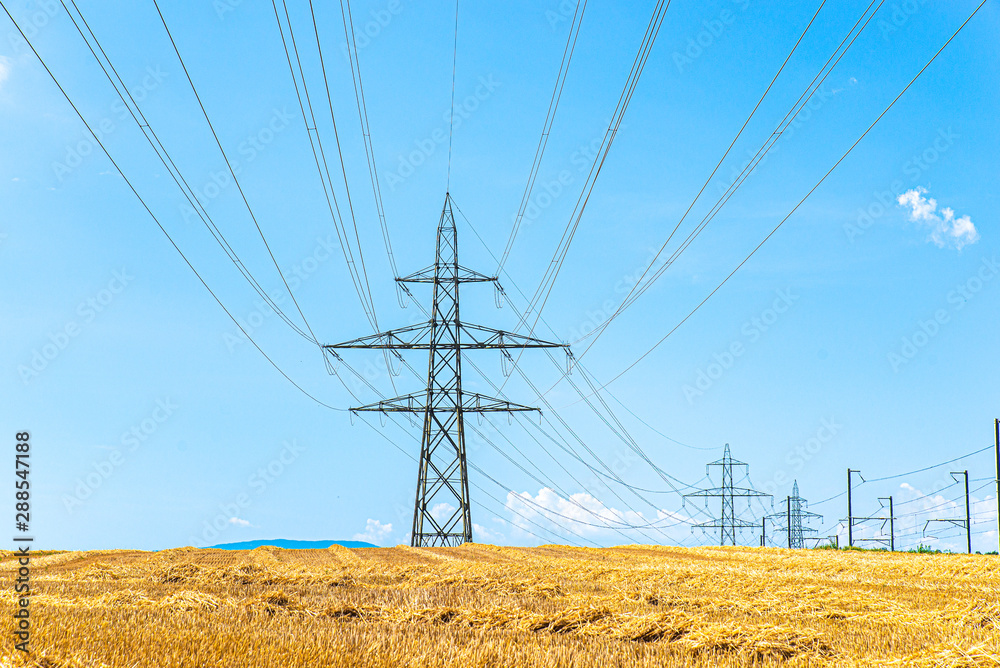 Huge power pylons with transmission lines over the field Huge power pylons with transmission lines over the field