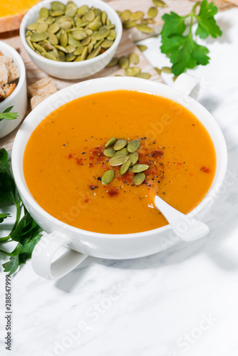 fresh soup of pumpkin and lentils on white background, vertical top view