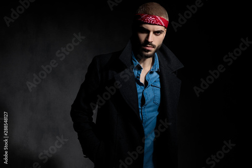 charming casual man wearing a longcoat on black background photo