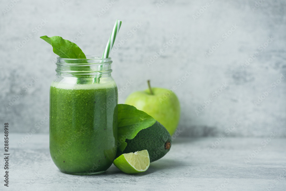 Green detox smoothie in glass jar from spinach, kiwi, lime, avocado on a light stone background Green detox smoothie in glass jar from spinach, kiwi, lime, avocado on a light stone background