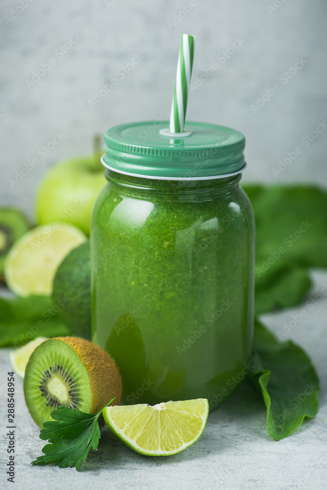 Green detox smoothie in glass jar from spinach, kiwi, lime, avocado on a light stone background Green detox smoothie in glass jar from spinach, kiwi, lime, avocado on a light stone background