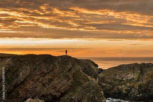 Person in shadow walking in a cliff on a sunset with an impresive orange sky