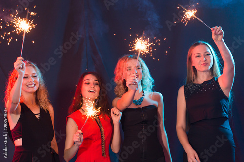 Party, holidays, nightlife and new year concept - happy young women dancing at night club disco