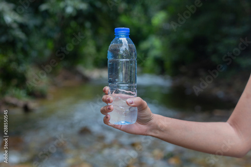 Close-up plastic water bottle in woman hand On a natural background
