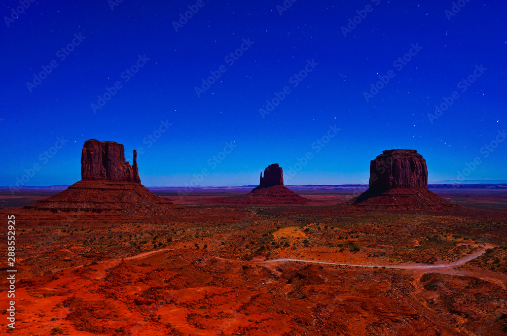 View of Monument Valley at night with lots of stars in the sky in Navajo Nation Reservation in USA.
