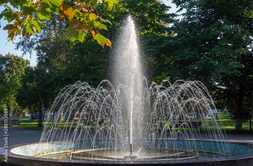 A fountain sprays water in sunny autumn weather.