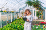Smiling woman phoning in a green house