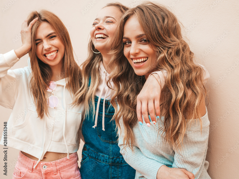 Portrait of three young beautiful smiling hipster girls in trendy summer clothes. Sexy carefree women posing on the street near wall.Positive models having fun.Hugging Portrait of three young beautiful smiling hipster girls in trendy summer clothes. Sexy carefree women posing on the street near wall.Positive models having fun.Hugging