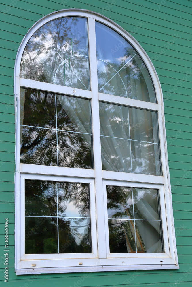 Obraz premium Reflection in a white plastic window in a green wall of a building