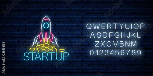 Glowing neon sign of business project startup with alphabet. Business symbol flying rocket starting in neon style.