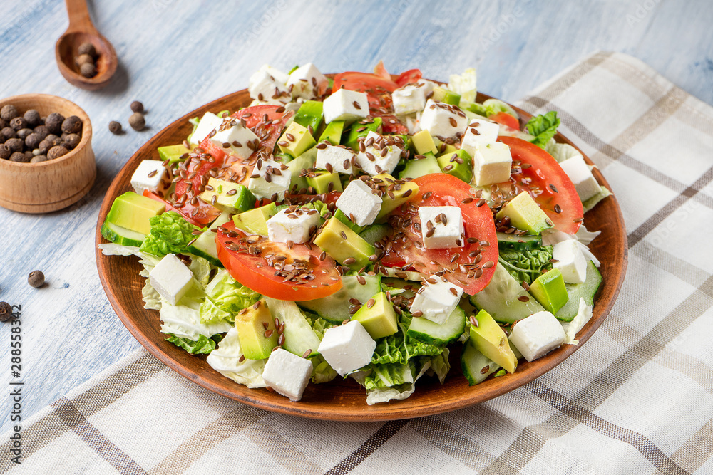 Close up view on large plate with tasty salad: tomato, feta cheese, avocado, asparagus and greens. Food photo background. Healthy, dieting, balanced salad