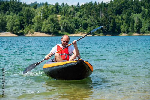 Man paddling in inflatable kayak on lake Lokve, in Gorski kotar, Croatia. Adventurous kayaking experience in a beautiful nature.