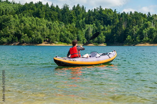 Woman paddling in inflatable kayak on lake Lokve, in Gorski kotar, Croatia. Adventurous experience in wild nature.