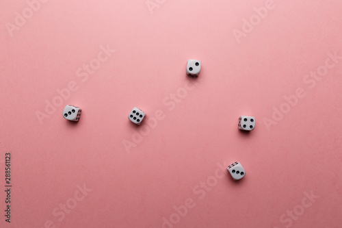 White gaming dice on pink background. Top view. Flat lay. Copy space. Game of chance concept. Close-up. Pastel colors
