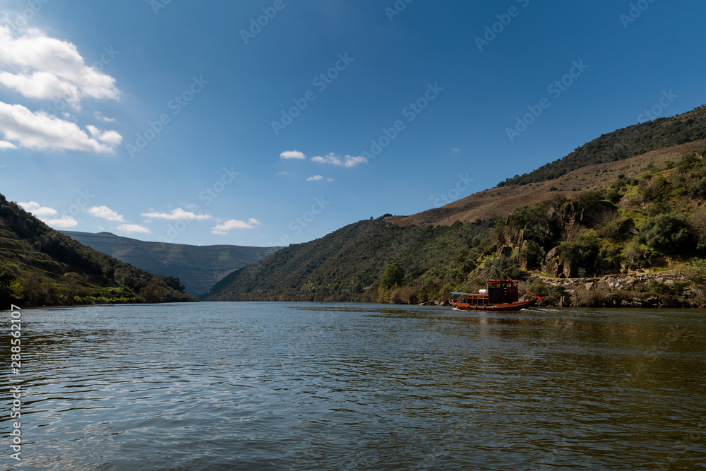 Scenic view of the Douro River with a traditional rabelo boat and terraced vineyards near the Tua village, in Portugal..