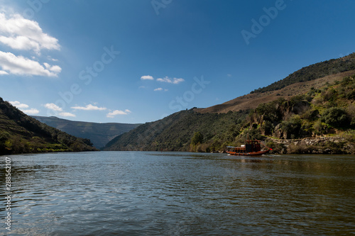 Scenic view of the Douro River with a traditional rabelo boat and terraced vineyards near the Tua village, in Portugal.. © Tiago Fernandez