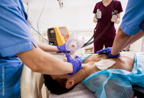 Doctors give resuscitation to a male patient in the emergency room. Cardiac massage photo