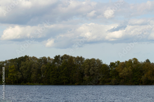 beautiful clouds green forest and river bank photo